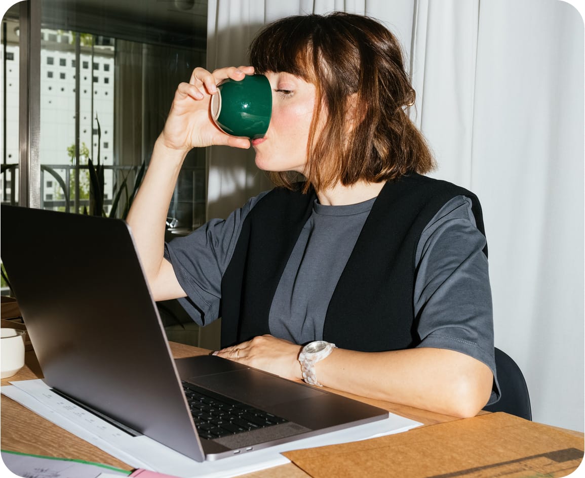 Woman drinking coffee while working in office